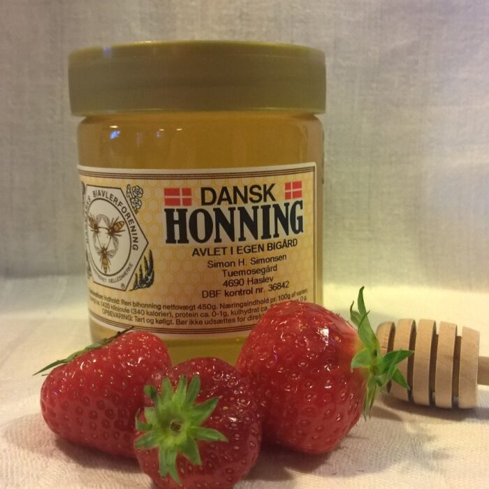Dansk honning produceret af Tuemosegård med røde jordbær foran