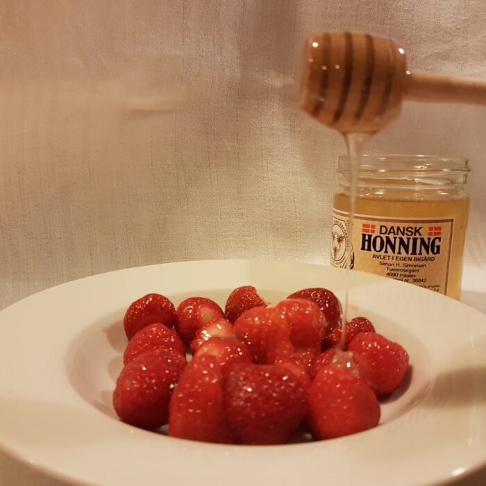 Skål med nye jordbær med dansk honning produceret af Tuemosegård